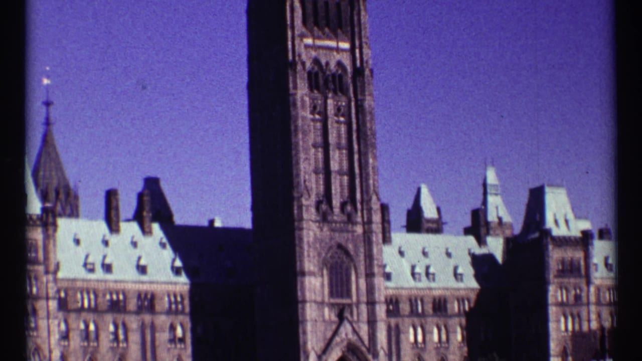 1967 Ottawa frame of Parliament Hill with the Peace Tower, Gothic Revival stonework, bright roofs, and clear sky.