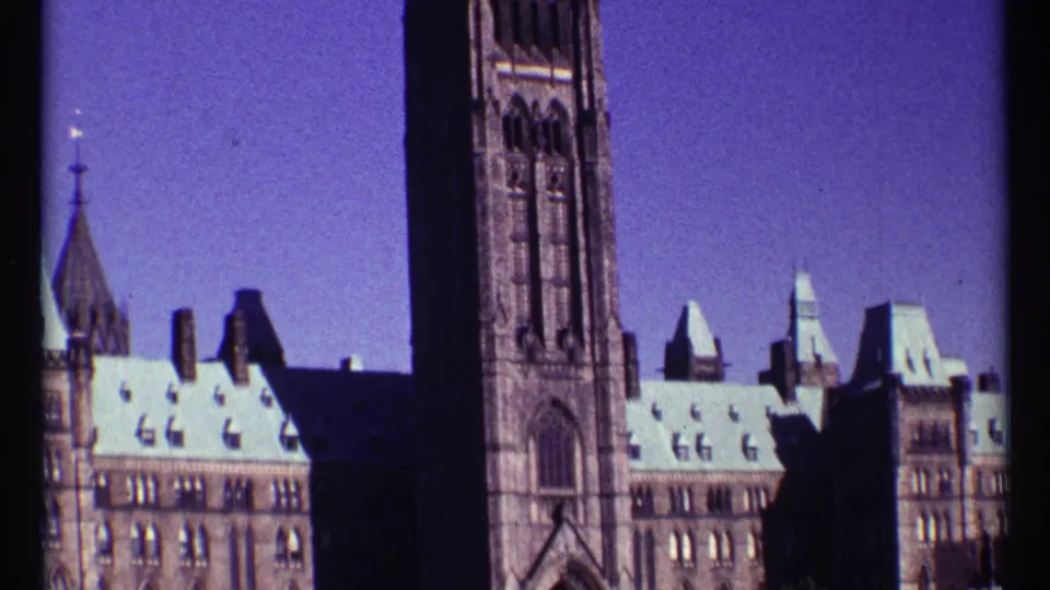 1967 Ottawa frame of Parliament Hill with the Peace Tower, Gothic Revival stonework, bright roofs, and clear sky.