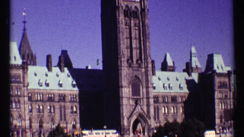 1967 Ottawa frame with the Peace Tower beside Parliament Hill rooftops, scanned with visible grain and dark frame edges.