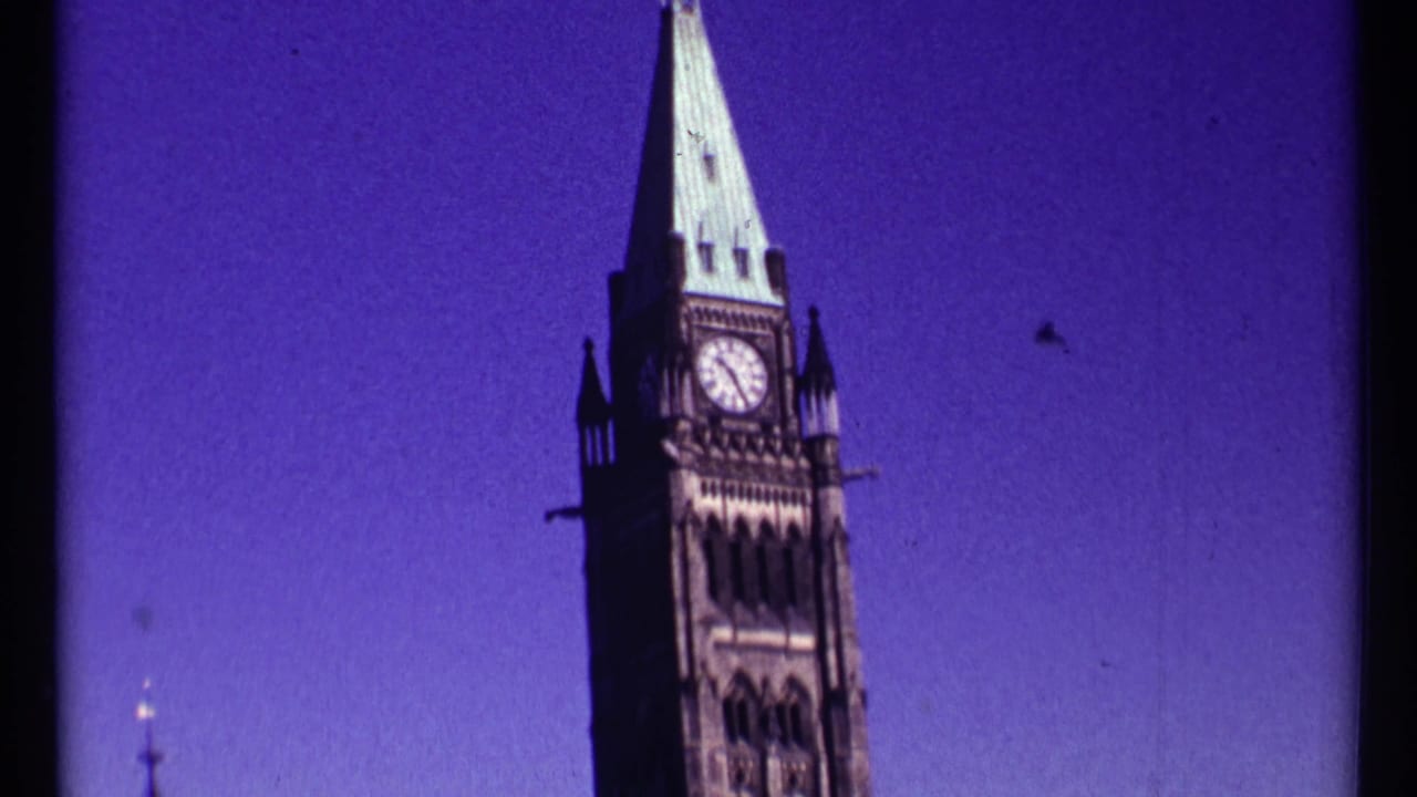 Close 1967 Ottawa view of the Peace Tower clock face and pointed green roof against a saturated sky.