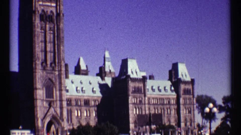 1967 Ottawa frame showing the Peace Tower side and Parliament Buildings with visible 8mm grain and color shift.