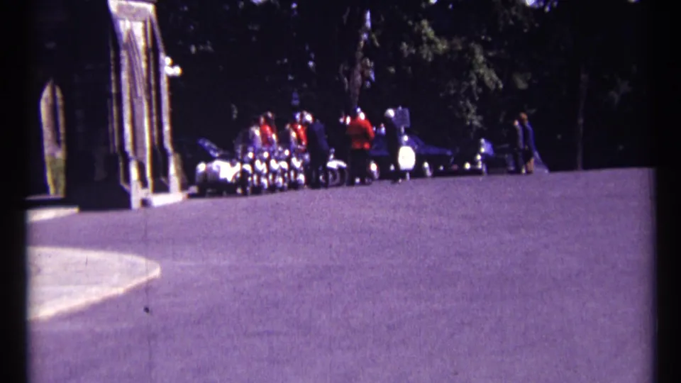 1967 Ottawa home-movie frame showing RCMP officers in red uniforms and visitors gathered near a stone building entrance.