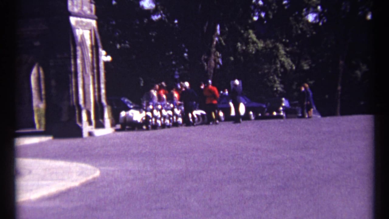 Wide view of people and RCMP officers gathered near a sunlit stone entrance.