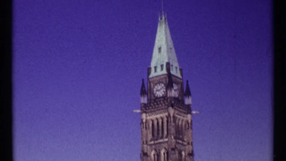 1967 Ottawa 8mm frame focused on the Peace Tower clock face and pointed spire against blue sky.