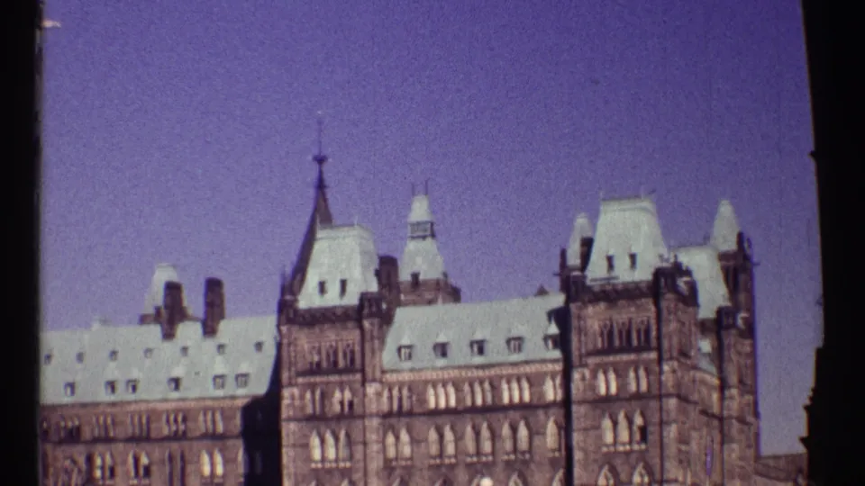 1967 Ottawa frame widening to show Parliament Buildings rooflines and stone facade, with part of the Peace Tower visible at the edge of the shot.