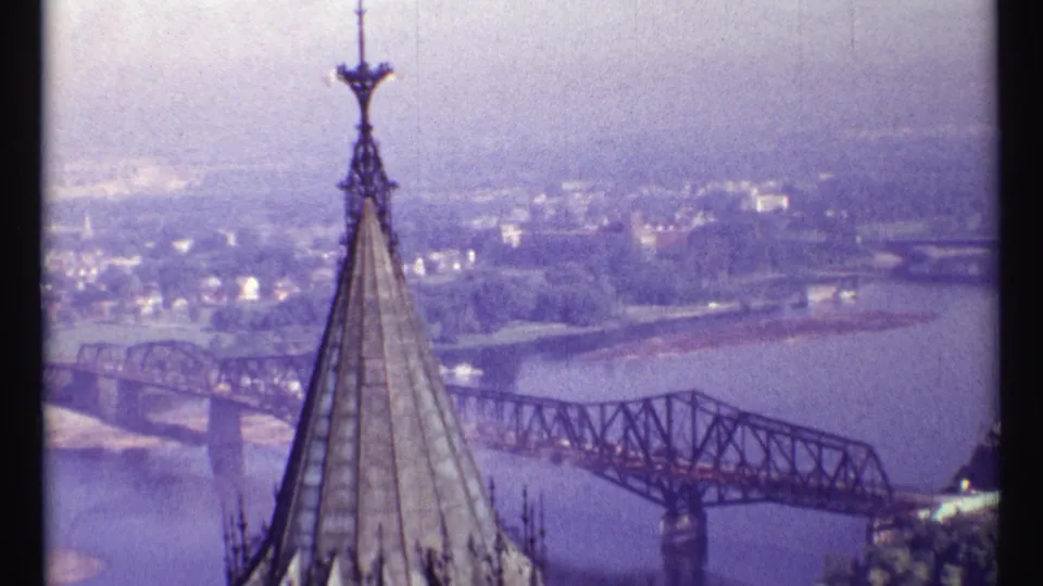 Elevated 1967 Ottawa view showing a tall Gothic-style spire, Alexandra Bridge, river, and distant shore.