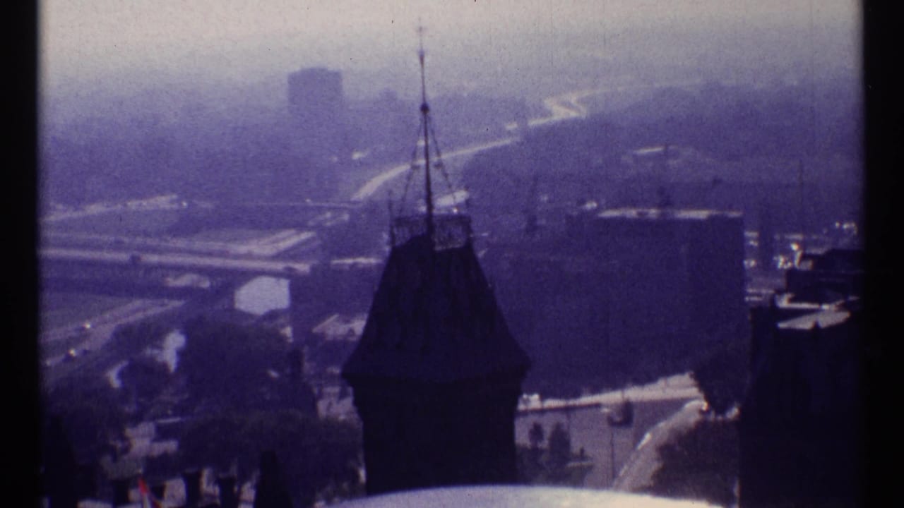 1967 Ottawa view from an elevated position, with a dark foreground spire and hazy bridge and road lines in the distance.