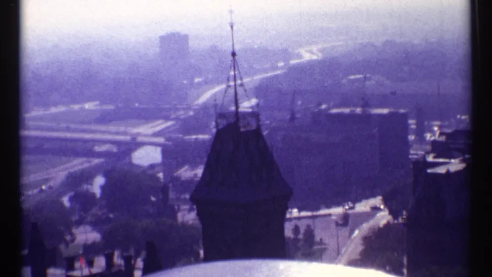 1967 Ottawa elevated view showing a dark spire against a hazy urban background of roads, bridges, and buildings.