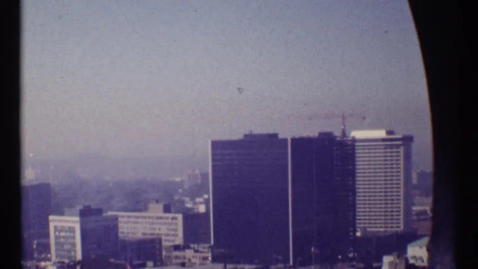 1967 Ottawa elevated view showing high-rise towers, a rooftop crane, low buildings, and distant haze across the city.