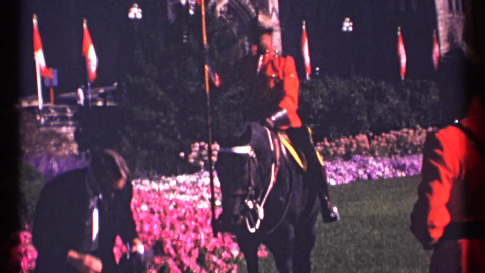 1967 Ottawa frame with a red-serge RCMP rider on a black horse beside Canadian flags, flowers, and another uniformed figure.