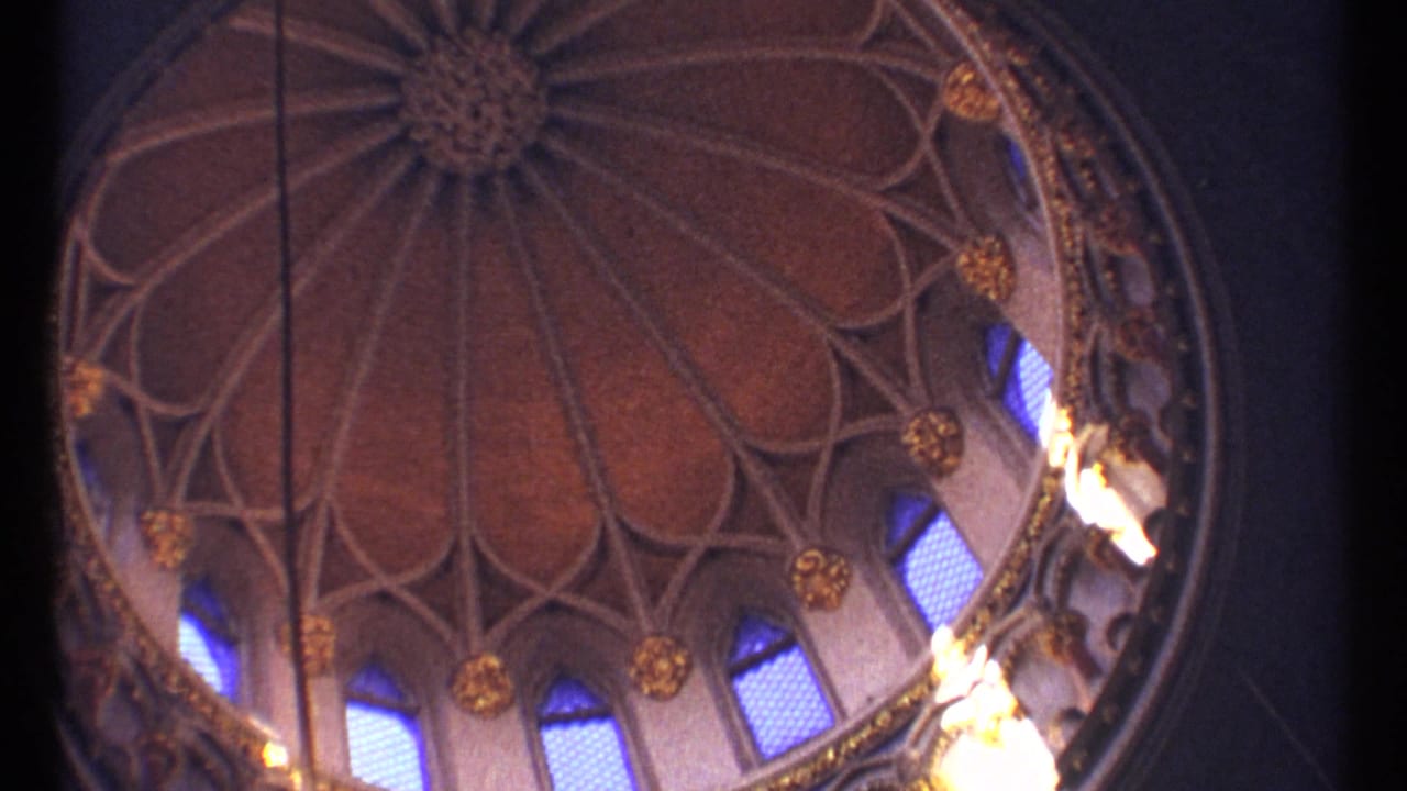 Decorated dome ceiling with arched windows, gold ornament, and dark vertical film edge.