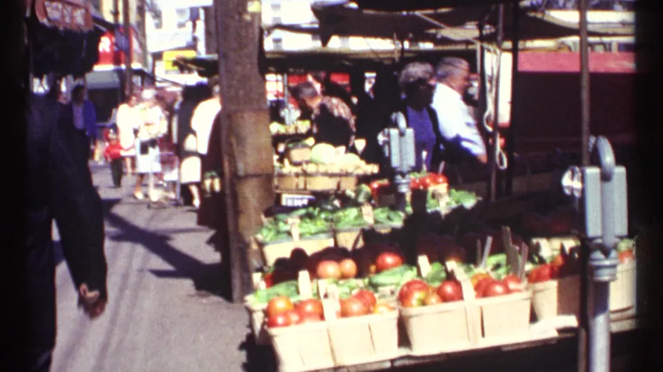 1967 Ottawa market scene with produce baskets in the foreground and pedestrians browsing beneath street canopies.
