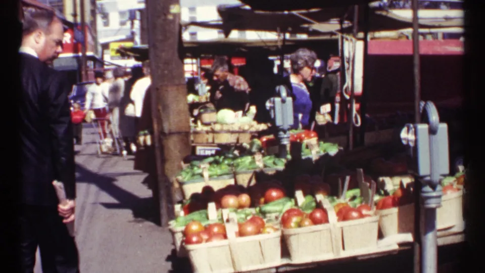 Outdoor Ottawa produce market with apples, greens, canopies, and shoppers passing through the sunlit street scene.