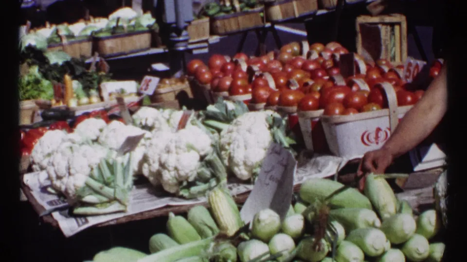 Ottawa outdoor market table in 1967 with cauliflower heads, tomato baskets, corn, squash, price signs, and a partial vendor arm.
