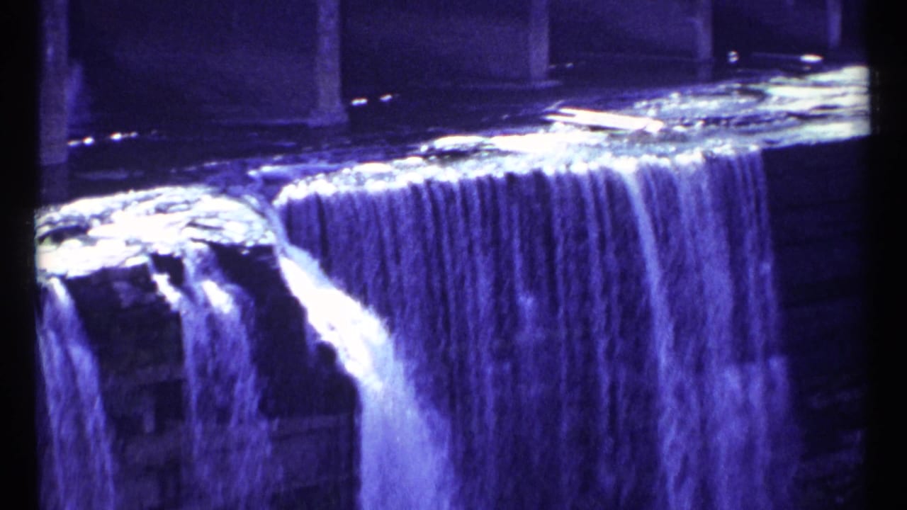 Water spills over tiered stone ledges with dark vertical structure in the center.