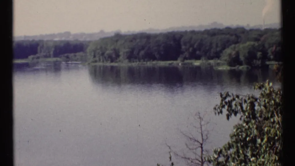1967 Ottawa-area river view with wooded shoreline, calm water, and distant landscape under a pale sky.