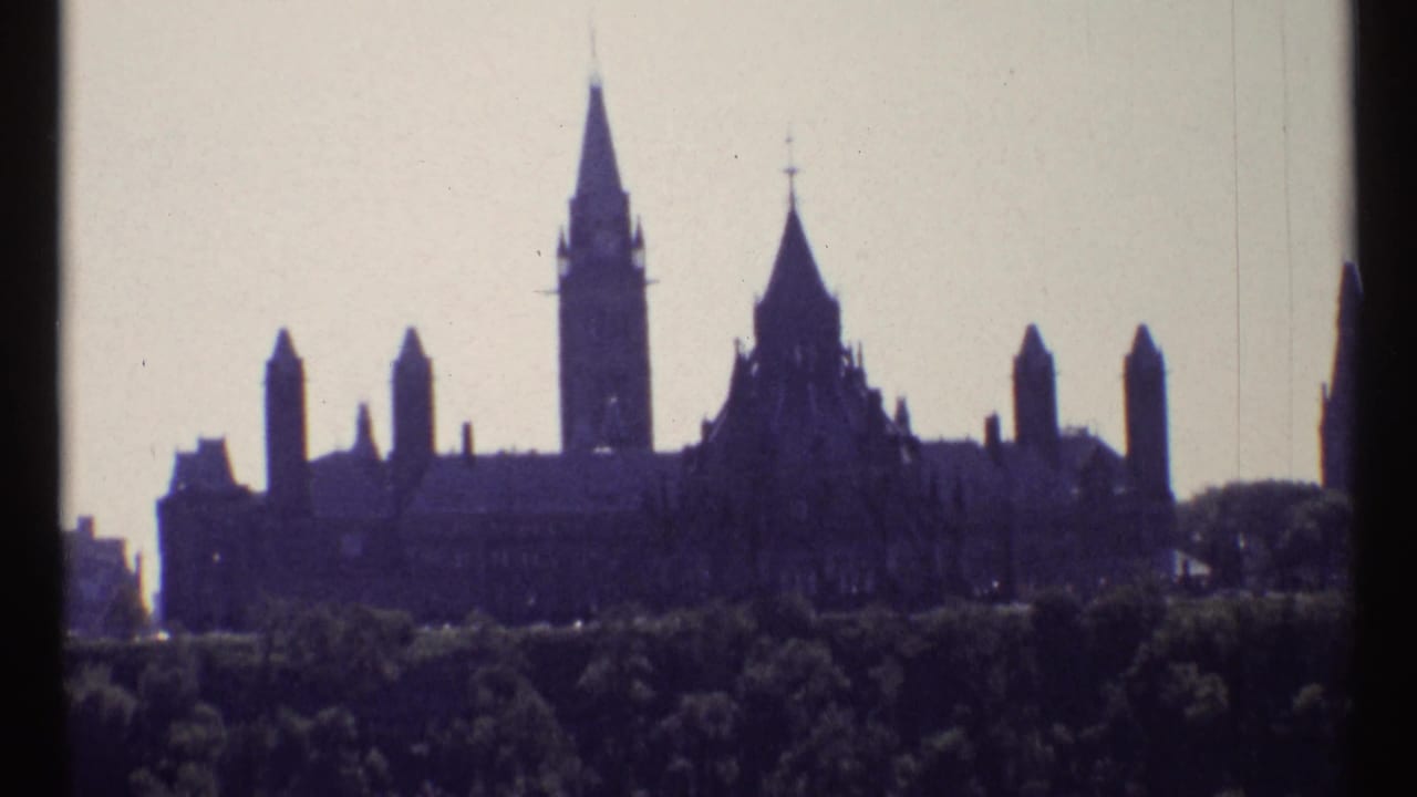 Parliament Buildings silhouette with Peace Tower above a dark line of trees.