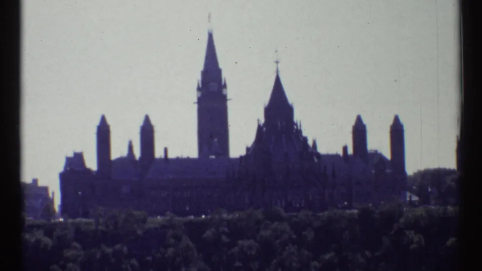 1967 Ottawa frame with Parliament Buildings, the Peace Tower, and flanking towers silhouetted above a dense tree line.