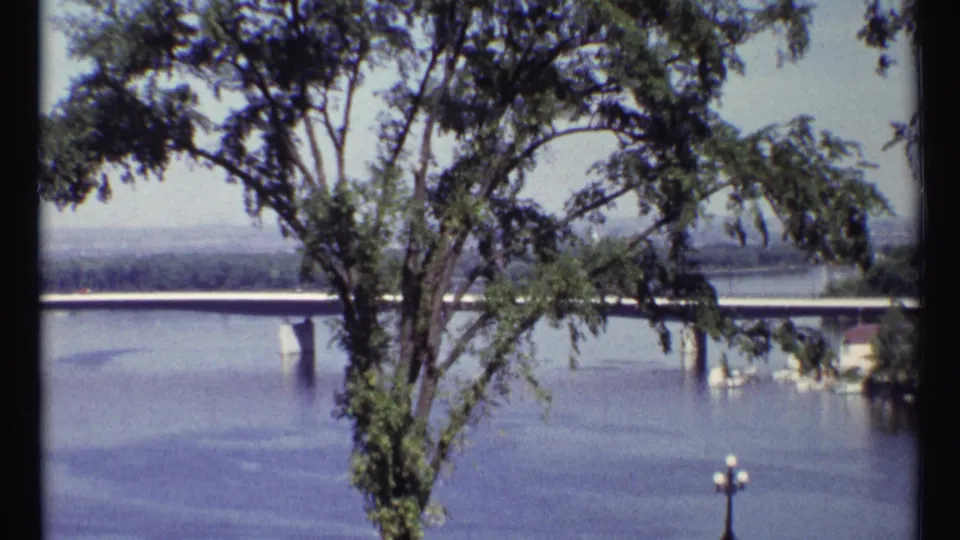 Ottawa river and bridge view framed by tree branches, with soft 8mm color and dark film borders visible.