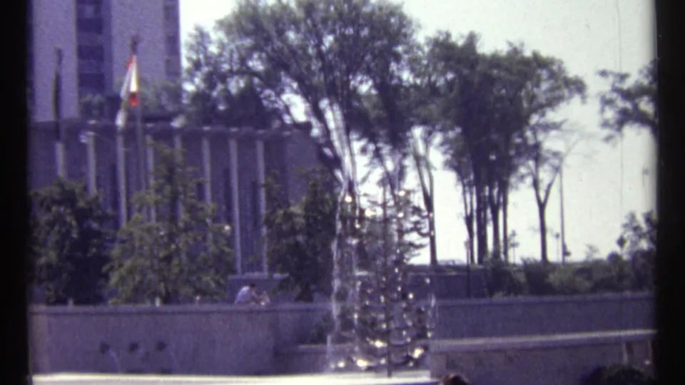 Ottawa plaza scene showing a fountain, tall trees, a flagpole, and part of a civic-looking building on 8mm film.