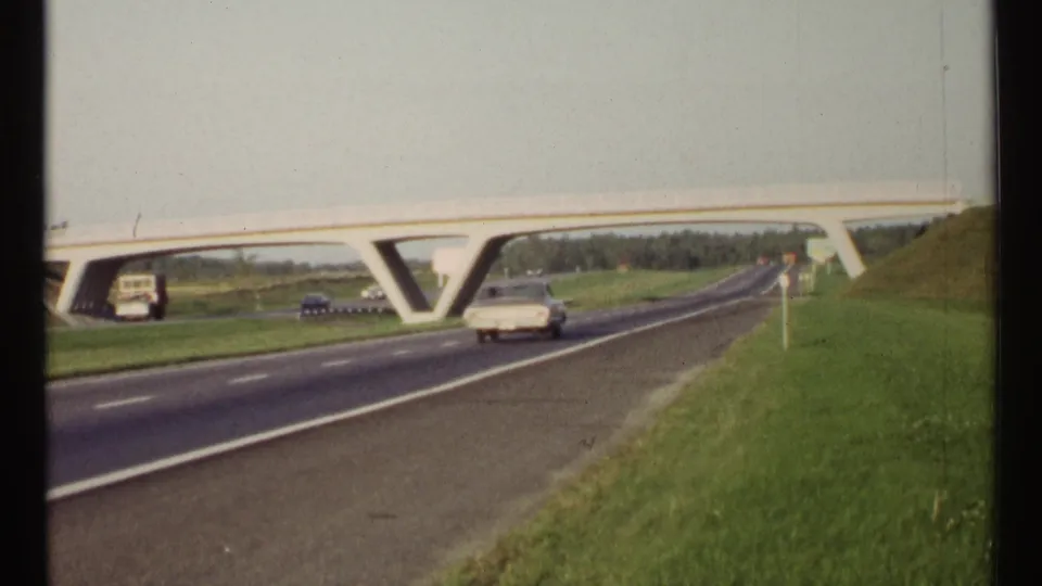 1967 Ottawa highway view with a white car approaching a concrete overpass, grassy roadside, and cars in the opposite lanes.