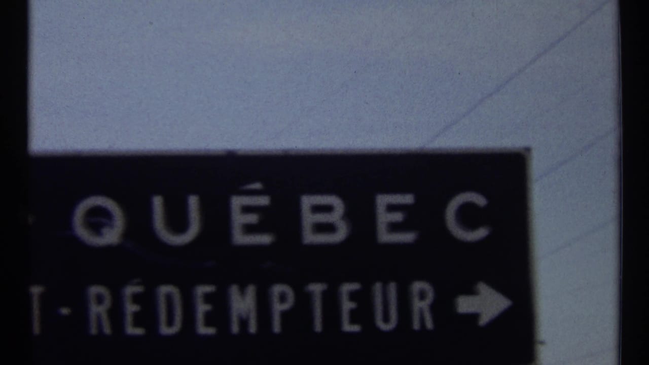 Close view of a dark road sign with white Québec lettering and partial St-Rédempteur text.