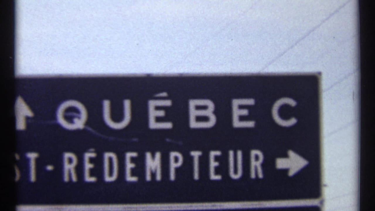 Directional sign reading Québec with partial St-Rédempteur text and arrows against a pale sky.