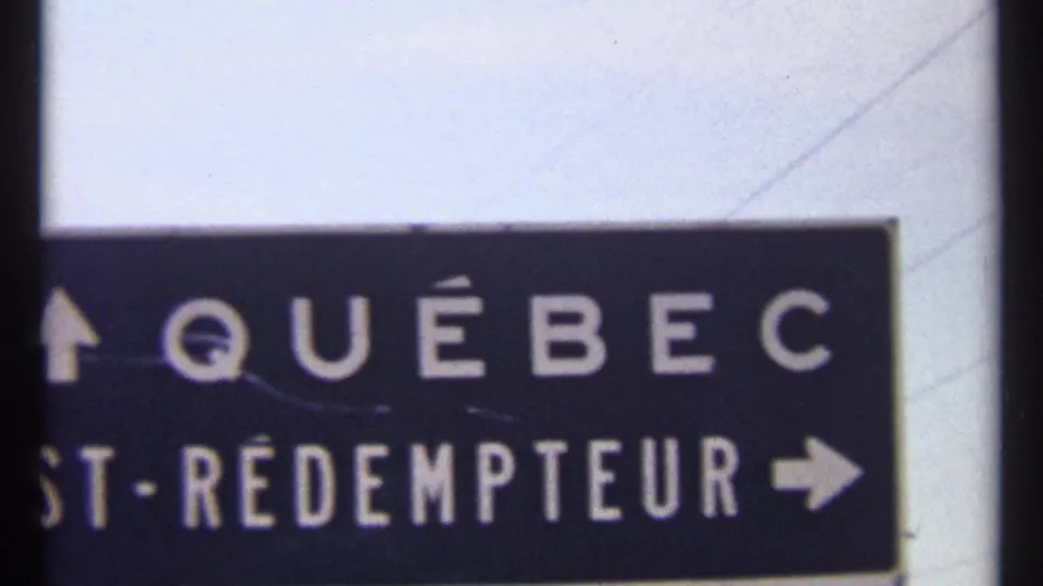 1967 Ottawa-area close frame of a dark Québec road sign with white lettering, partial St-Rédempteur text, and visible film grain.