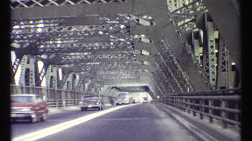 1967 Ottawa home-movie view from a moving vehicle crossing a steel truss bridge with cars ahead.