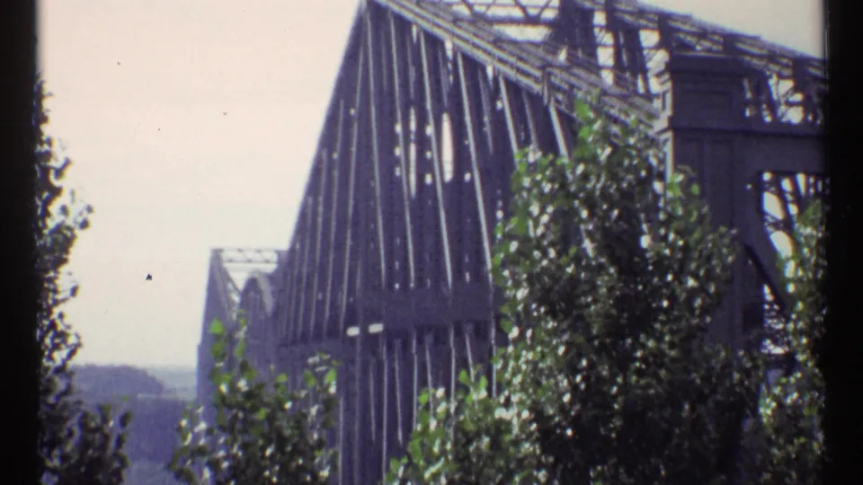 1967 Ottawa exterior view of the steel truss bridge structure, partly obscured by green foliage.