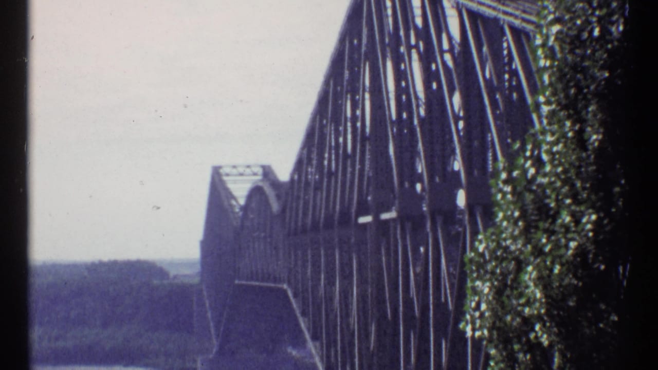 Steel bridge span viewed close up with trees along the right edge.