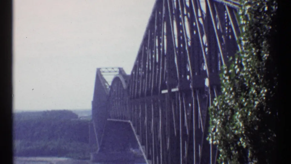 1967 Ottawa frame showing Alexandra Bridge steelwork at close range, with trees at right and a hazy riverside background.