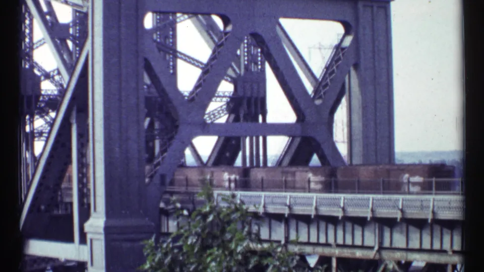 1967 Ottawa home-movie frame showing freight cars partly obscured by the bridge railing and dark steel structure.