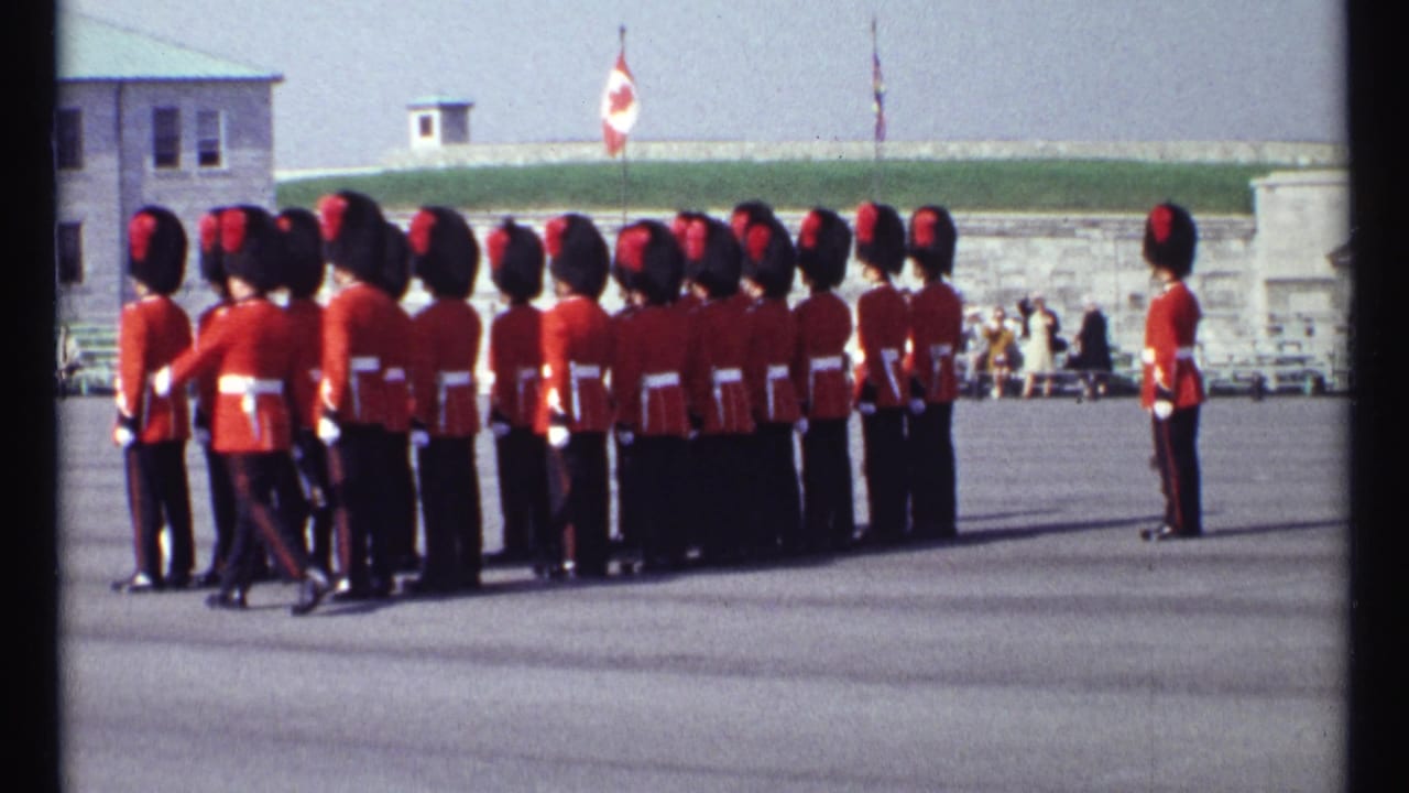 Ceremonial guards in red tunics stand in formation on an open parade ground.