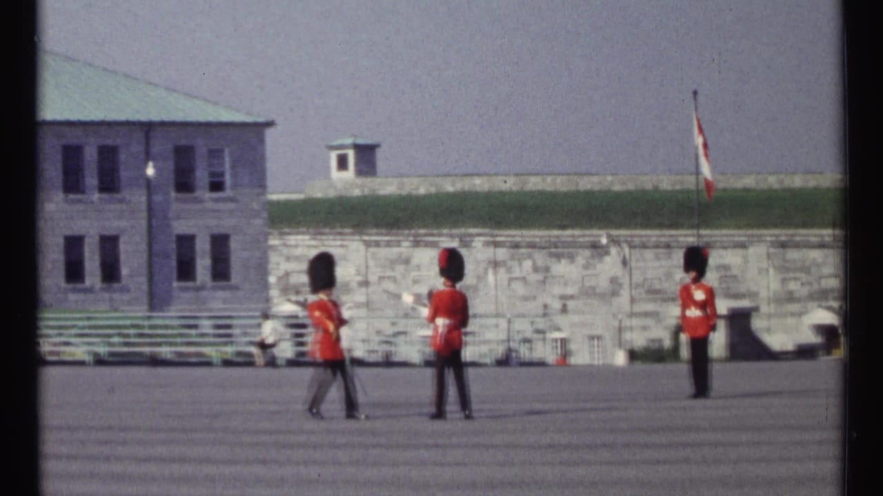 One guard marches between two stationary guards on a paved courtyard.