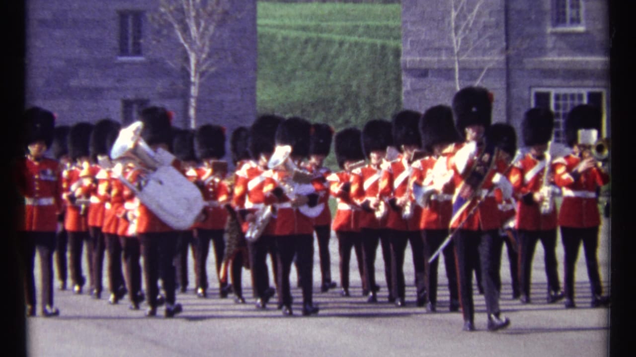 Red-uniformed band members march in formation with a white sousaphone near center.
