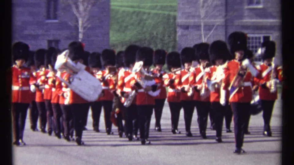 Close 8mm view of the Ottawa ceremonial band formation, with red-coated musicians and a prominent white sousaphone.