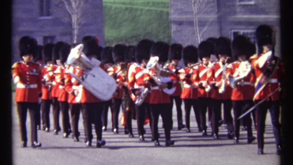 1967 Ottawa 8mm frame showing a red-uniformed marching band approaching, with musicians, drums, and brass instruments visible.