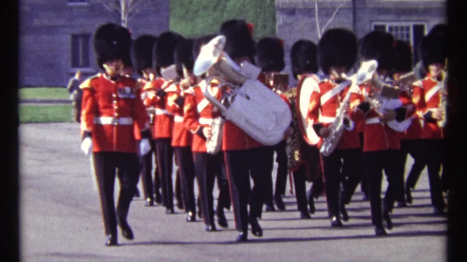A red-uniformed guard at front left leads the ceremonial band as musicians march behind him in the Ottawa courtyard.