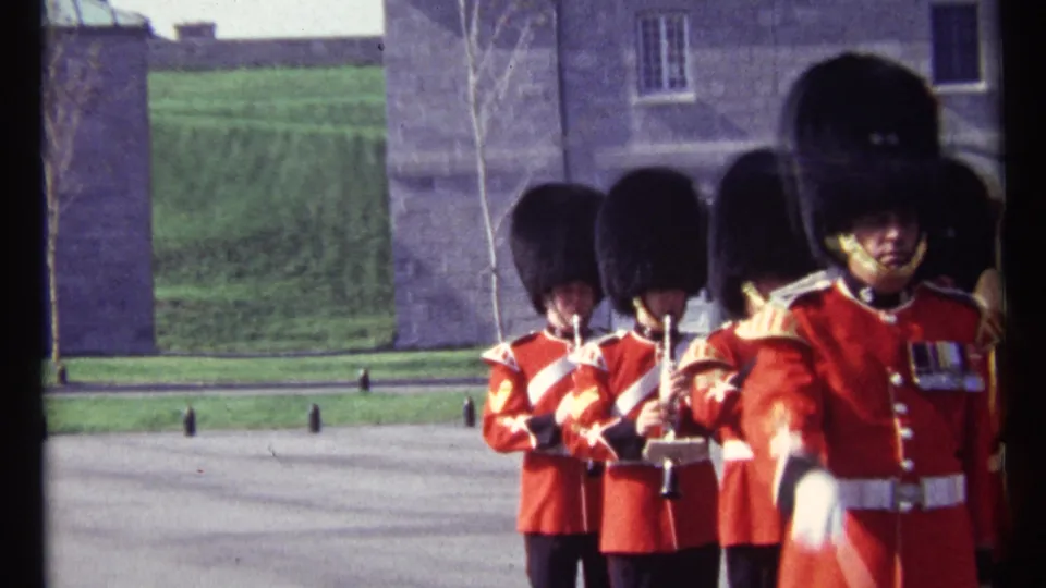Near the end of the 1967 Ottawa clip, guards in red tunics and tall black hats pass close to the camera with instruments behind them.