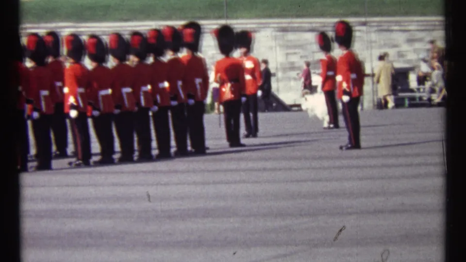 Ottawa 1967 frame showing a ceremonial band in red tunics and black hats arranged in lines with onlookers in the distance.