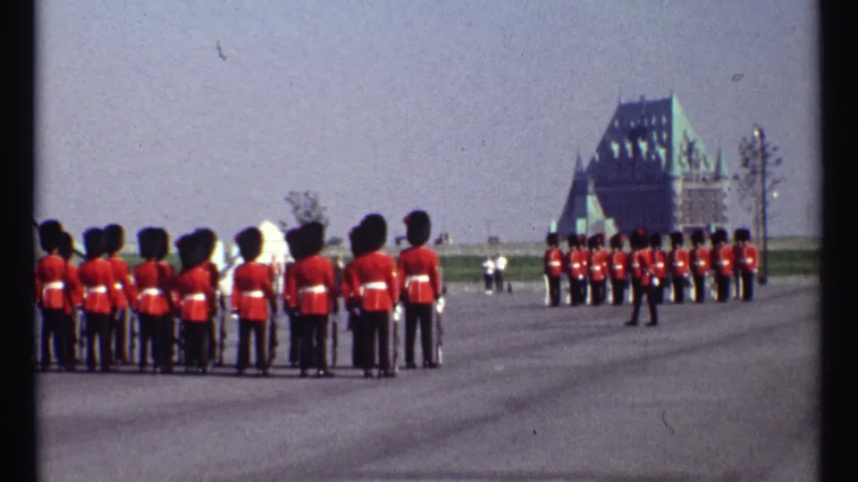 A visitor-shot 1967 Ottawa view shows red-coated guards holding formation on a broad paved ground near Parliament-style architecture.