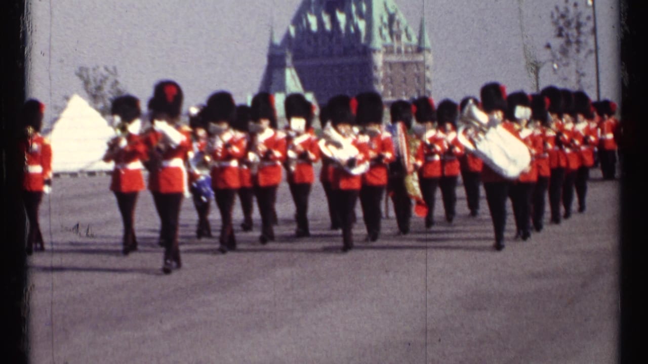 Marching band in red uniforms moving in formation with drums and brass instruments visible.