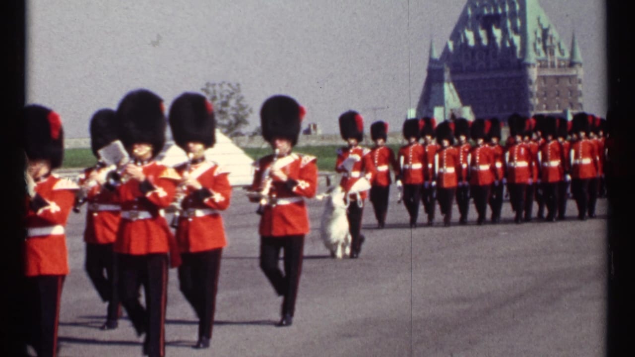 RCMP band members in red uniforms march with brass instruments as a white goat follows near the formation.