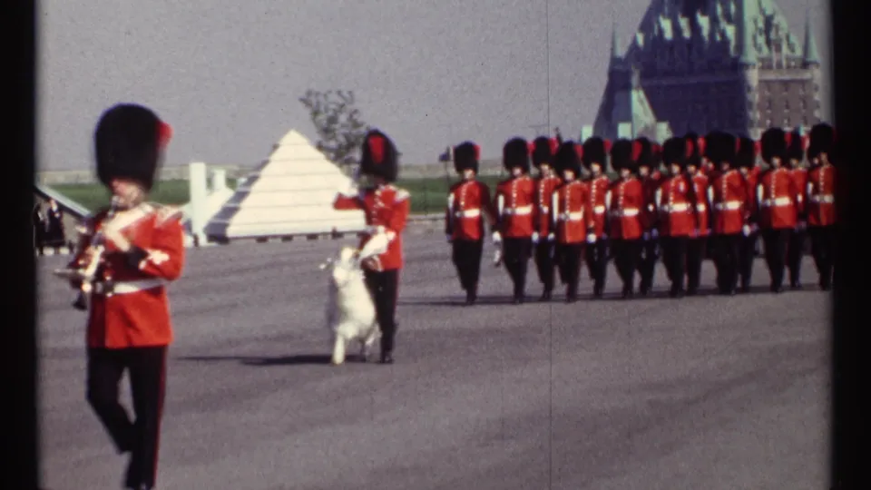 1967 Ottawa 8mm frame with a foreground RCMP musician, white goat mascot, and red-uniformed formation on a paved ceremonial ground.