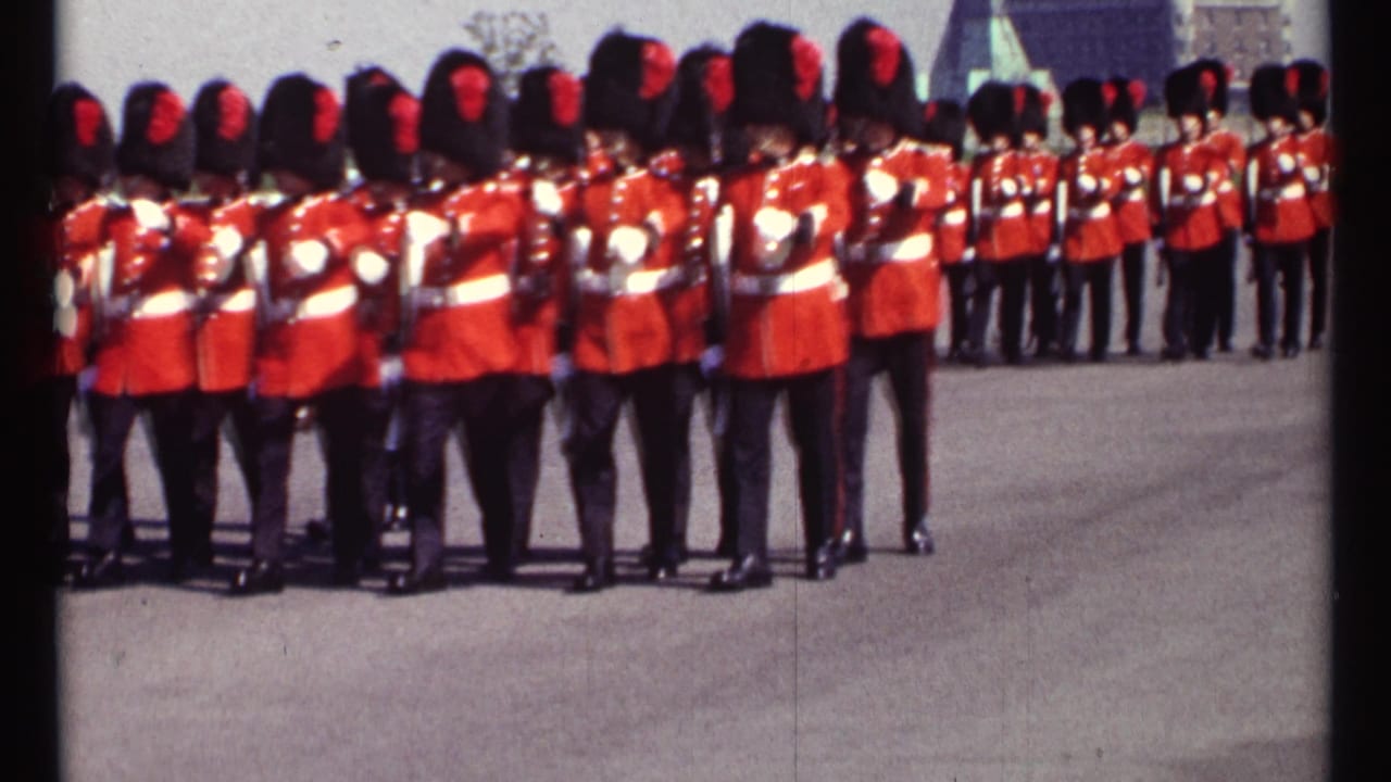 Guards in red tunics and bearskin hats marching with rifles on a paved courtyard.
