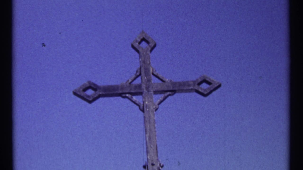 Weathered metal cross framed against a deep blue sky.