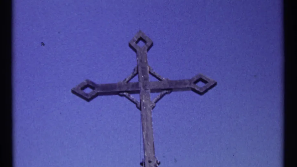 1967 Ottawa 8mm frame showing a weathered metal cross isolated against a saturated blue sky.