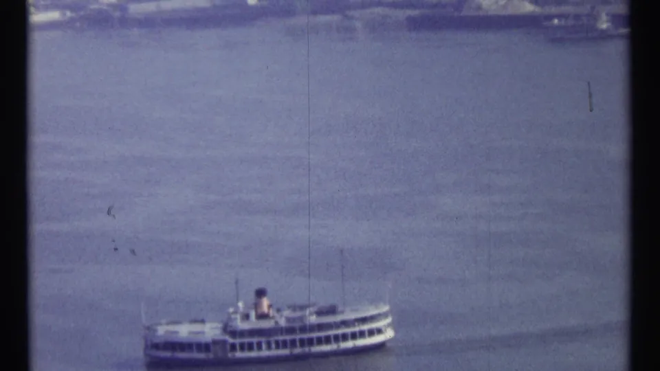 Soft 8mm frame from Ottawa showing a distant passenger boat on broad water, with shoreline detail near the top edge.