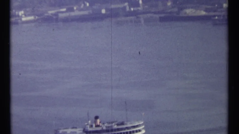 1967 Ottawa home-movie frame with a distant passenger boat low on the water under soft, grainy exposure.